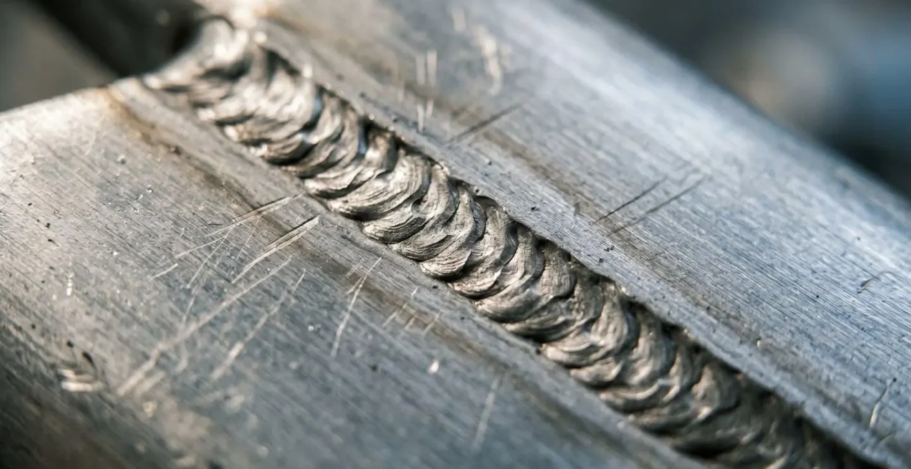 Extreme close-up macro shot of metal weld joint texture showing fatigue stress concentration point