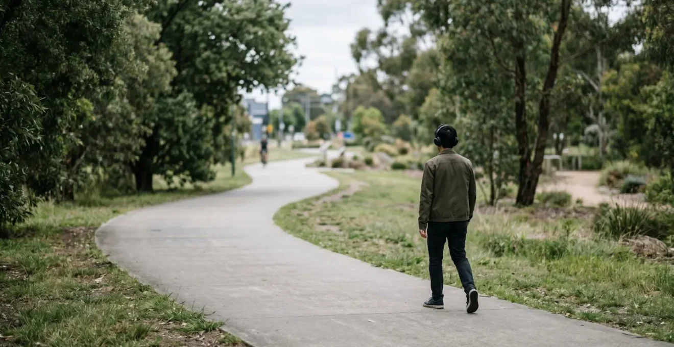 Environmental wide shot of shared path showing pedestrian with headphones creating unpredictable hazard for approaching mobility users