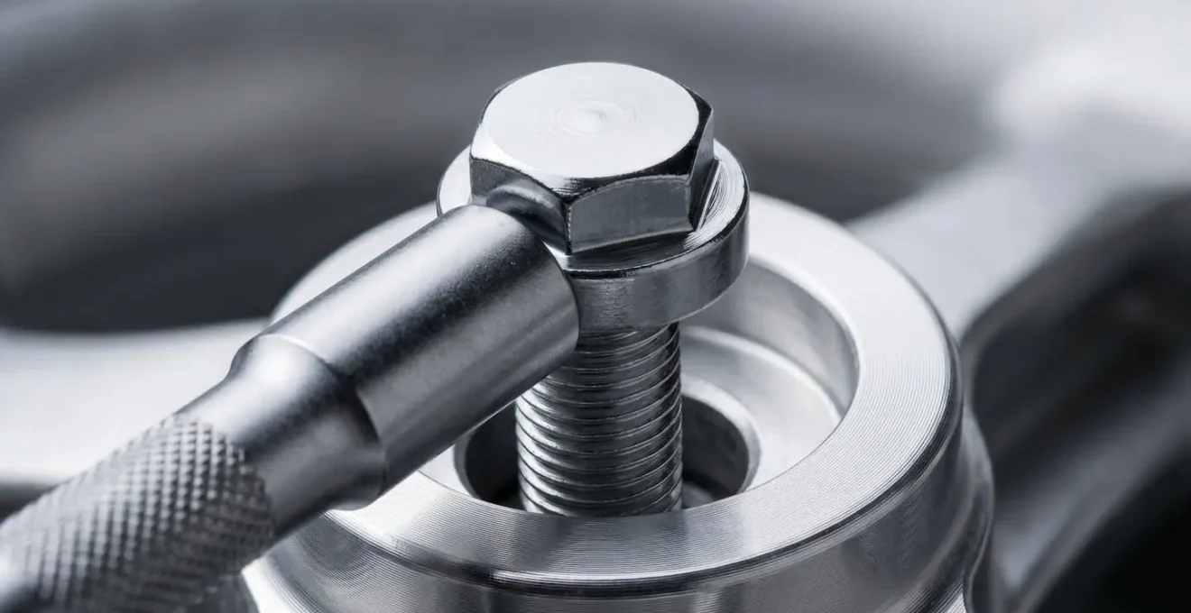 Macro close-up photograph of a socket wrench tightening a chrome wheel bolt on a mobility scooter hub with precise mechanical detail